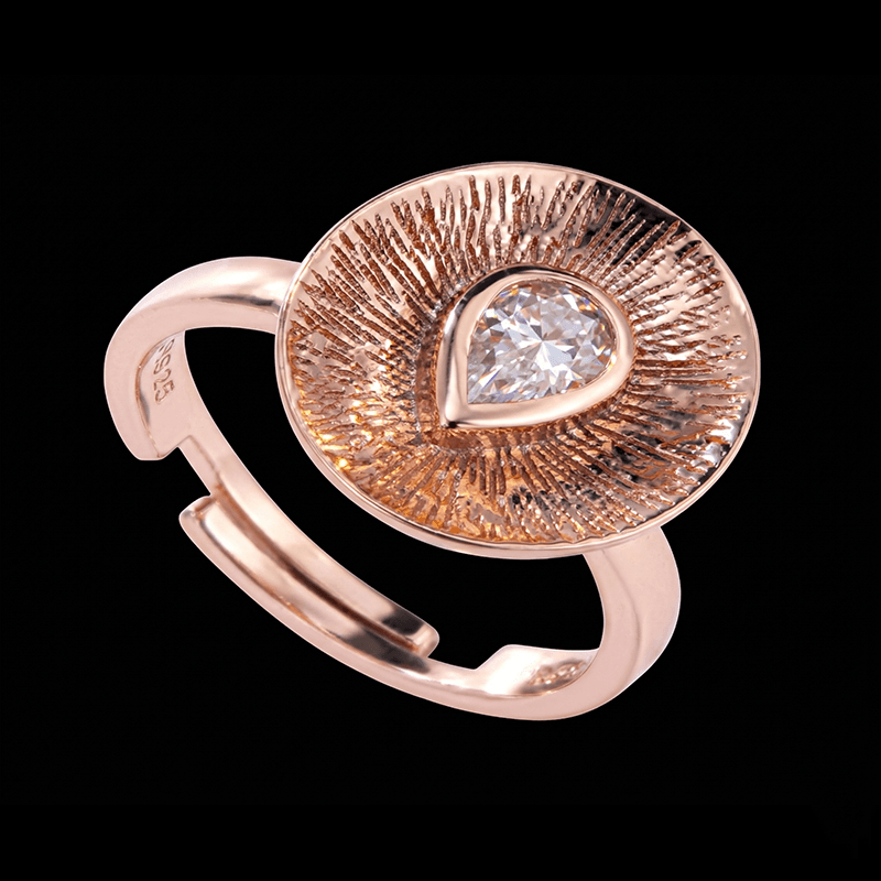 Pear cut moissanite ring with a textured rose gold sunburst halo and adjustable open band.