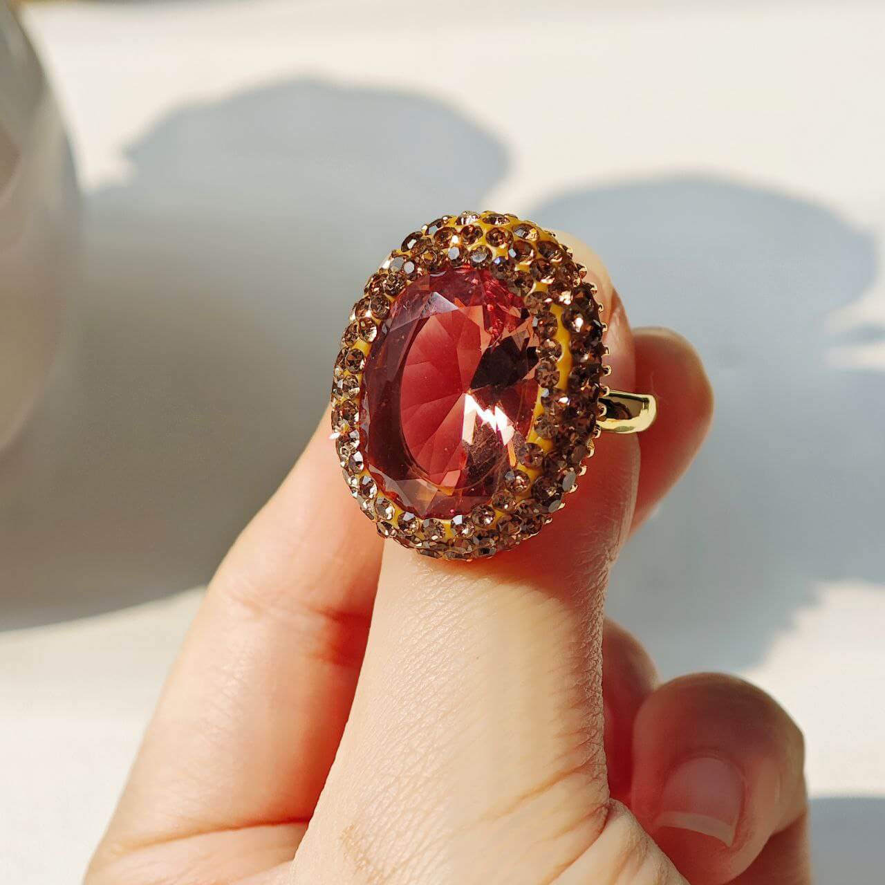 Astralee Jewelry Vintage Zultanite Ring with a large red gemstone held on a blurred background